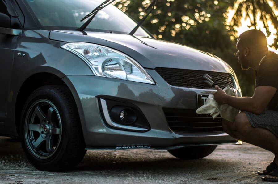 A person carefully washing a car with a microfiber mitt to avoid scratches.